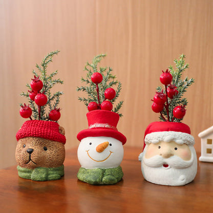 Three decorative planters shaped like a bear, snowman, and Santa Claus on a wooden surface.